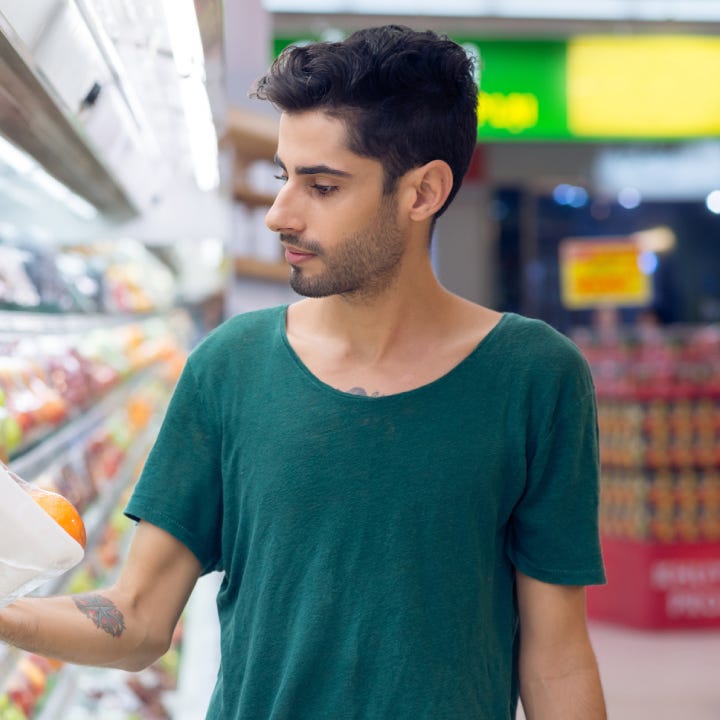 Person shopping at grocery store choosing oranges in the supermarket